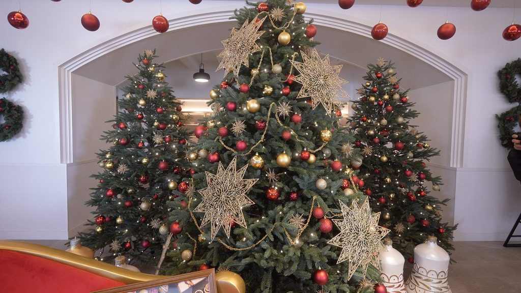 レクー沖縄北谷 リゾート＆スパ館内のクリスマス装飾。複数のツリーに赤と金のオーナメントや大きな星が飾られている